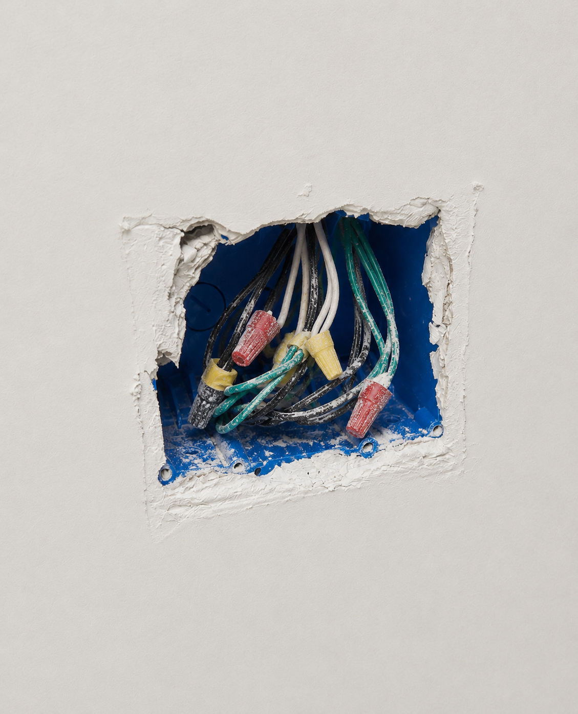 Unprotected electrical box with drywall compound on the box and wiring